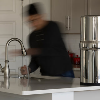 Man moving around in a kitchen with a BOROUX water filter on the counter top