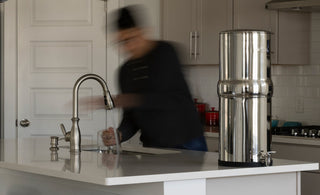 Man moving around in a kitchen with a BOROUX water filter on the counter top