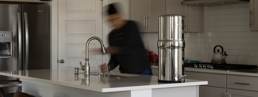 Man moving around in a kitchen with a BOROUX water filter on the counter top
