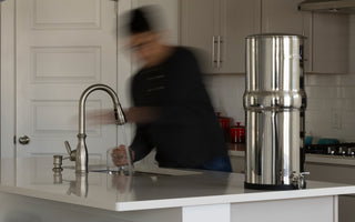 Man moving around in a kitchen with a BOROUX water filter on the counter top