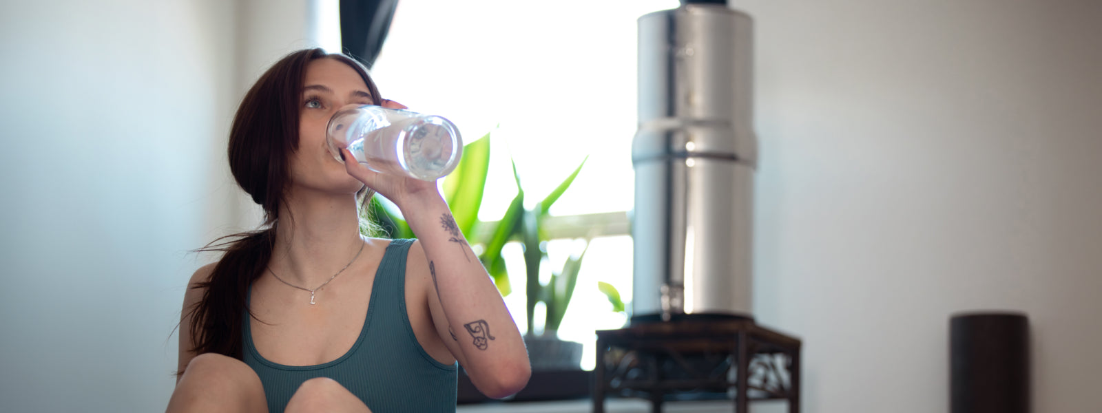 Girl take a break from yoga and drinking BOROUX water from a glass BOROUX bottle