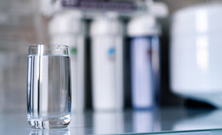 Glass of water on counter top next to a reverse osmosis (RO) water filter system