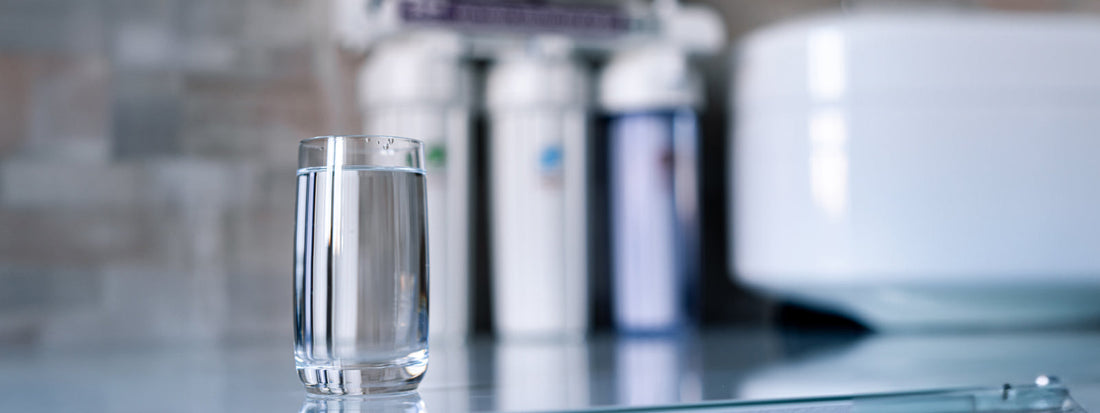 Glass of water on counter top next to a reverse osmosis (RO) water filter system