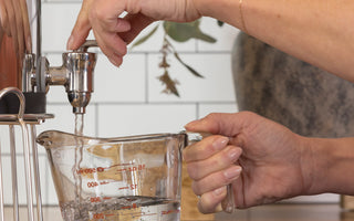 Woman pouring BOROUX water into a measuring cup to start making sourdough 