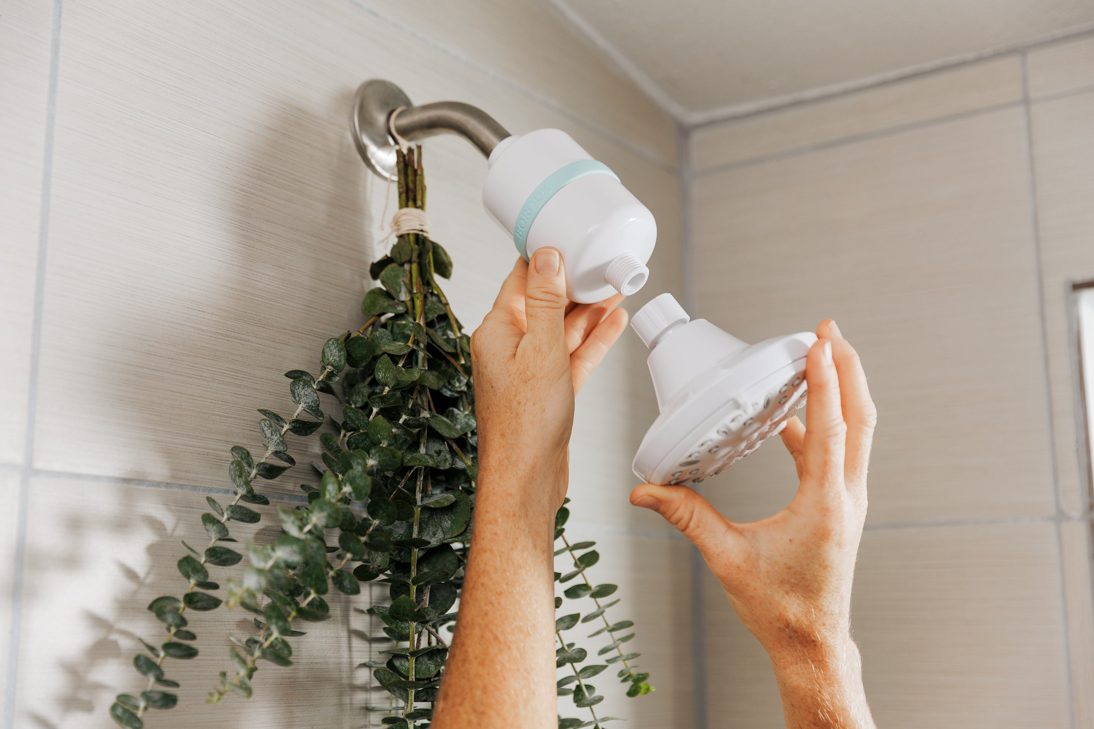 Person holding a shower head and filter in a bathroom setting